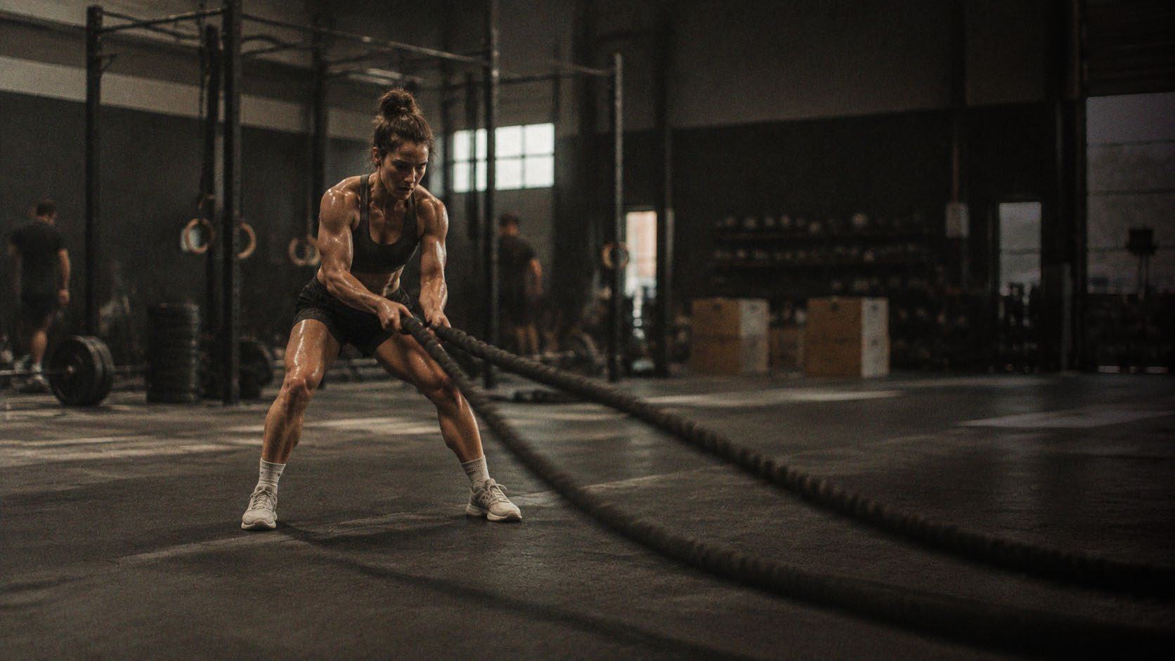 Atleta entrenando con cuerdas de batalla en un gimnasio